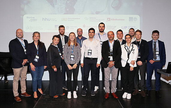 Gruppenfoto aller Teams die gepitcht haben, auf der Bühne des Pitch4MED.