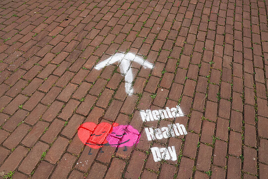 Der Schriftzug "Mental Health Day" ist mit Farbe auf den Pflastersteinboden gesprayt und ein Pfeil zeigt die Gehrichtung an